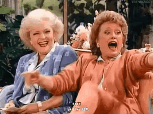 Two Women Laughing and Pointing on Couch