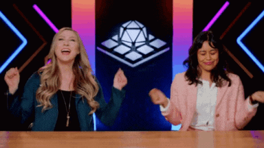 Two Women Laughing With Arms in Air at Table