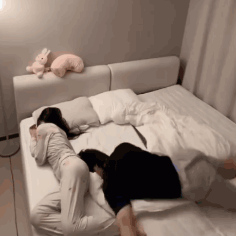 Two Women Laying on Bed With Stuffed Rabbit