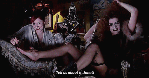 Two Women On Couch Saying Tell Us About It Janet GIF
