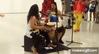 Two Women Playing Drums and Singing into Microphones