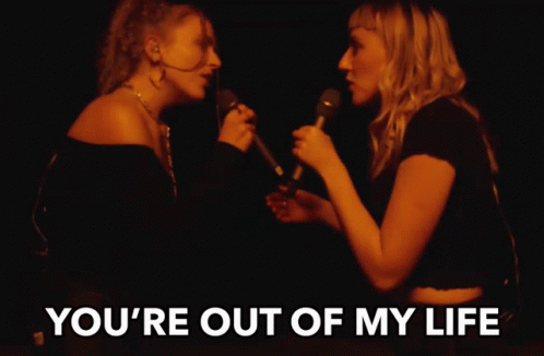 two women singing into microphones with the words " you 're out of my life " above them