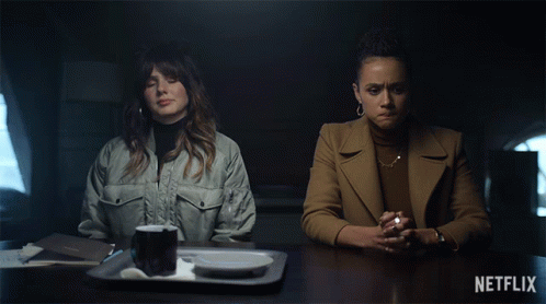Two Women Sit At A Table With Netflix Written On The Bottom Left GIF