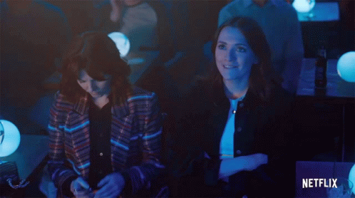 Two Women Sit In A Dark Room With A Netflix Logo In The Corner GIF
