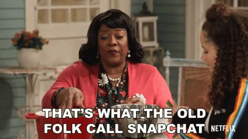 Two Women Sitting At A Table With The Words That 'S What The Old Folk Call Snapchat Written On The Bottom GIF