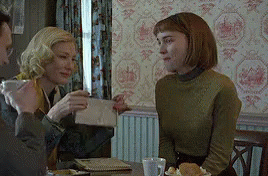 Two Women Sitting at Table One Holding Envelope