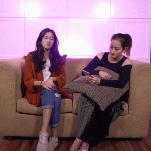 Two Women Sitting On Couch Looking At Cell Phones GIF