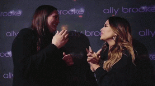 Two Women Standing in Front of Ally Brooke Wall