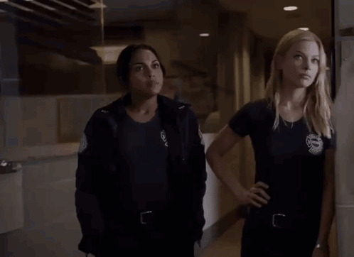 Two Women Standing In Hallway Looking At Something GIF