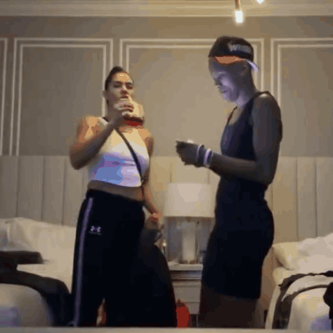 Two Women Standing Next To Each Other In A Bedroom Wearing Under Armour Sweatpants GIF