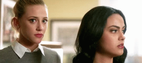 Two Women Standing Next To Each Other Looking At Each Other In A Room GIF