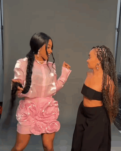 Two Women Standing Next To Each Other One In A Pink Dress And The Other In A Black Dress GIF