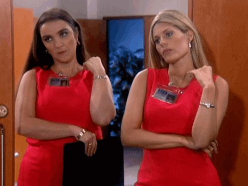 Two Women Standing Next To Each Other Wearing Red Dresses GIF