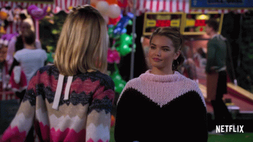 Two Women Standing Next To Netflix Logo GIF