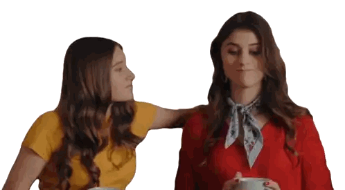 two women standing next to each other with one holding a cup