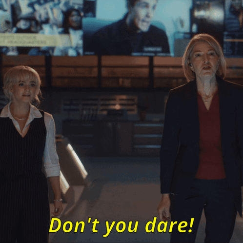 Two Women Standing Next To Each Other With The Words " Don 'T You Dare " In Yellow Letters GIF