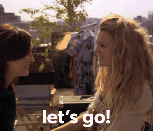 Two Women Standing Together Saying Let's Go