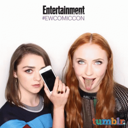 Two Women Sticking Their Tongues Out In Front Of A Sign That Says Entertainment #Ewcomiccon GIF