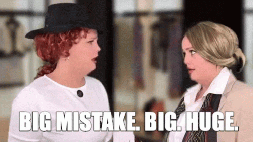Two Women Talking in a Room One Wearing Top Hat