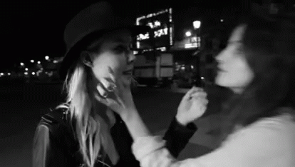 Two Women Touching Faces At Night GIF