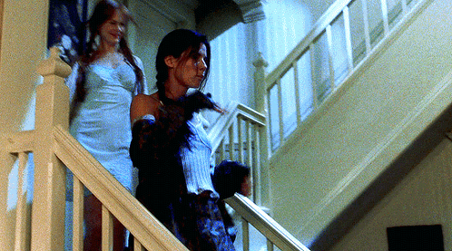 two women walking down a set of stairs in a house
