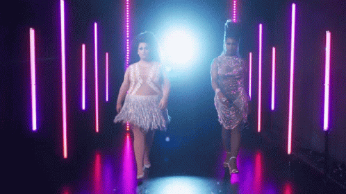 Two Women Walking In Dark Purple-Lit Room GIF