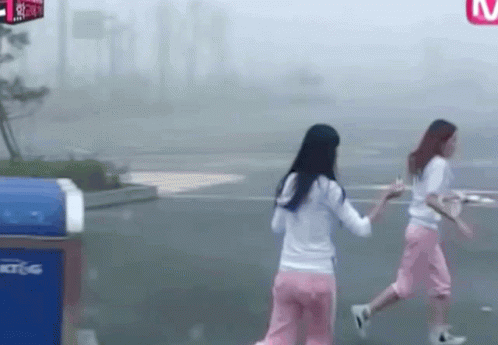 Two Women Walking Past Sign Saying M