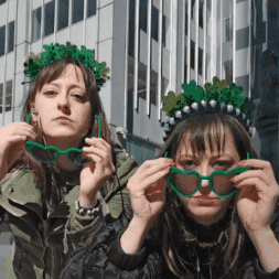 Two Women Wearing Green Glasses And A Green Crown GIF