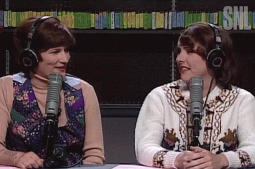 Two Women With Headphones In Front Of Microphones GIF