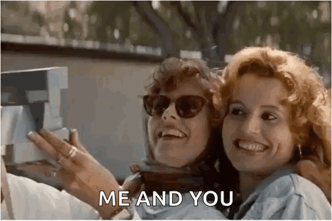 Two Women Wearing Sunglasses Are Taking A Selfie With A Polaroid Camera . GIF