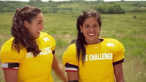 Two Women Wearing Yellow Shirts That Say The Challenge Are Standing Next To Each Other In A Field GIF