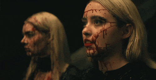 Two Women With Blood On Their Faces Look At Each Other GIF