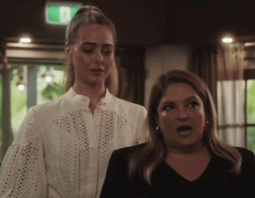 Two Women With Green Exit Sign Above GIF