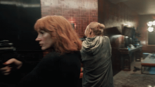 Two Women With Red Hair Are Standing In A Room GIF