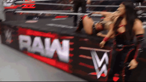 Two Women Wrestling In Front Of A Raw Banner GIF