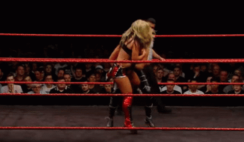 Two Women Wrestling in Ring With Referee