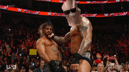 Two Wrestlers Are Dancing In Front Of A Crowd And A Sign That Says Raw GIF