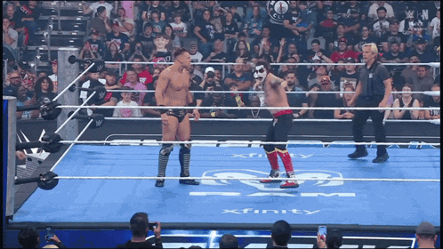 Two Wrestlers Are Standing In A Ring With Xfinity Written On The Floor GIF