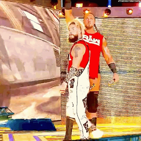 two wrestlers are standing next to each other and one of them is wearing a raw shirt