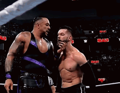 Two Wrestlers Are Standing Next To Each Other In A Ring . GIF