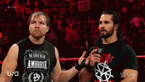 Two Wrestlers Are Standing Next To Each Other In A Wrestling Ring And One Of Them Is Wearing A Shirt That Says Ambrose GIF