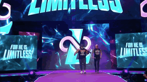 Two Wrestlers Are Walking Down A Purple Ramp With The Words For He Is Limitless On The Screen Behind Them GIF