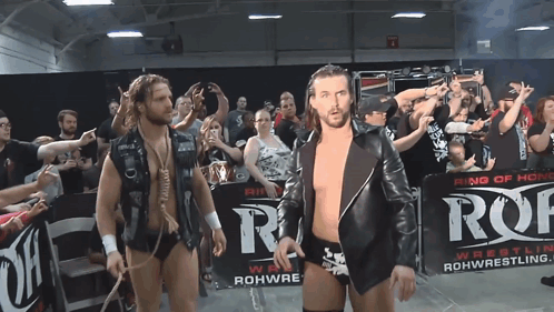 Two Wrestlers Are Walking In Front Of A Sign That Says Ring Of Honor GIF