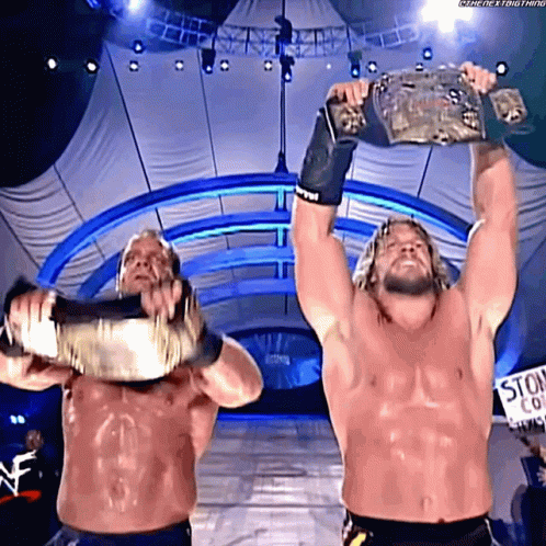 Two Wrestlers Holding Up Championship Belts