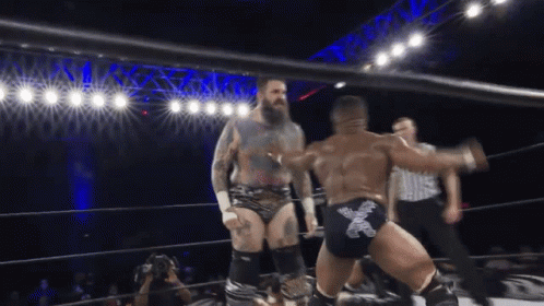 Two Wrestlers In A Ring With One Wearing A Pair Of Shorts With The Letter X On Them GIF