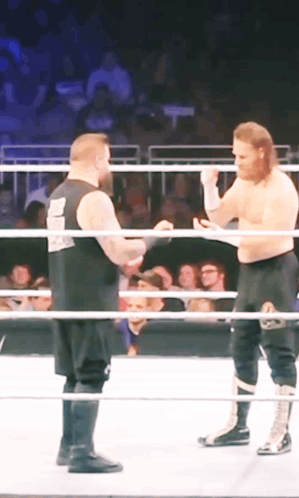 Two Wrestlers In A Ring With One Wearing A Shirt That Says ' Smackdown ' GIF