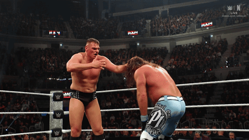Two Wrestlers In A Ring With The Word Raw On The Wall GIF
