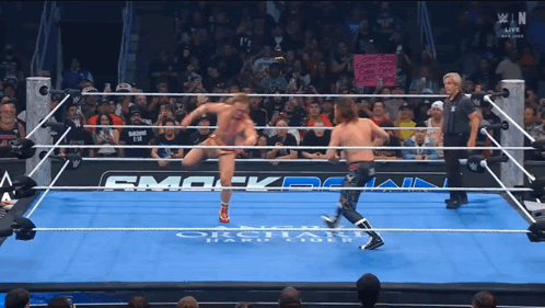 Two Wrestlers in Ring With Smack Down Sign