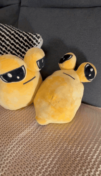 Two Yellow Stuffed Animals Are Sitting On A Bed Next To A Pillow GIF