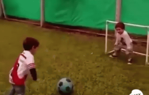 Two Young Boys Are Playing Soccer On A Soccer Field With A Goal . GIF